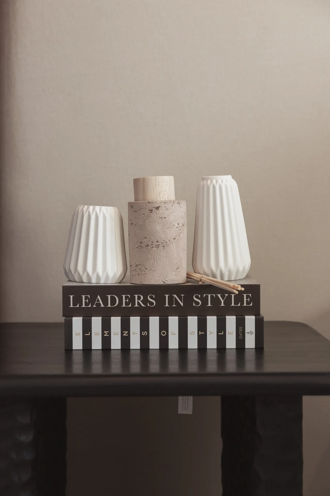 Bedside table styled with white vases and a stack of books. Interior design photography for Aziza Home by MRPS in Dubai.