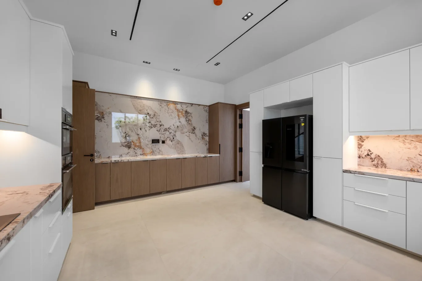 Kitchen with walnut and white units and marble worktops, unfurnished five-bedroom villa in Al Furjan, Dubai.