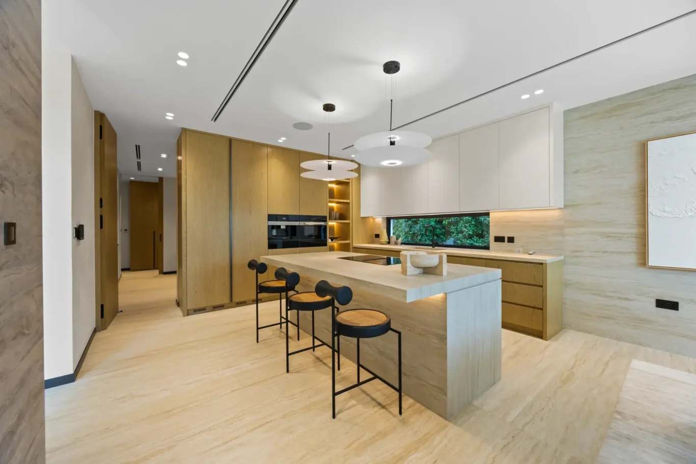 Kitchen island with bar stools and built-in ovens, luxury villa in Jumeirah Islands, Dubai.
