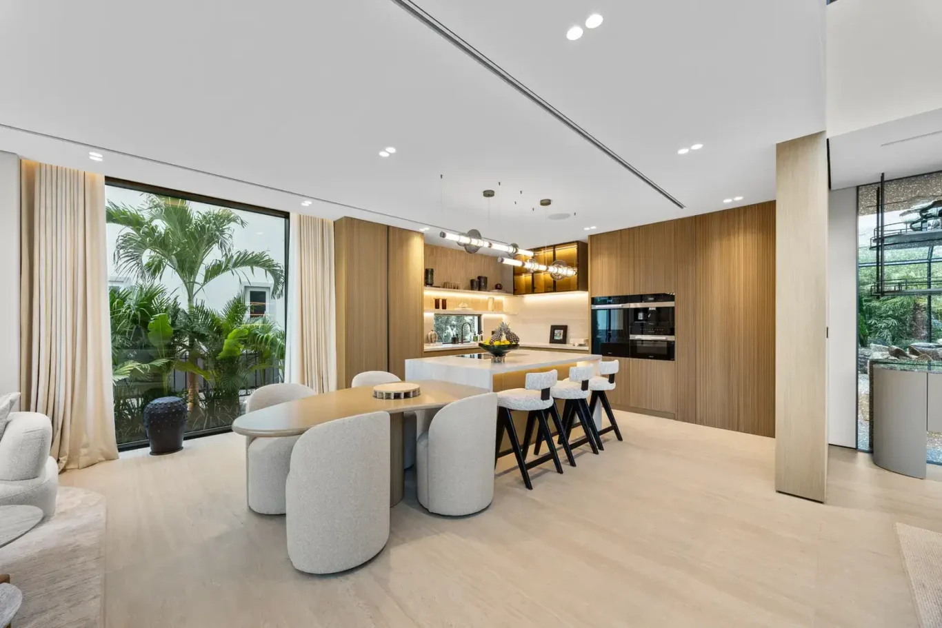 Family dining table and open kitchen with garden views, luxury villa in Jumeirah Islands, Dubai.