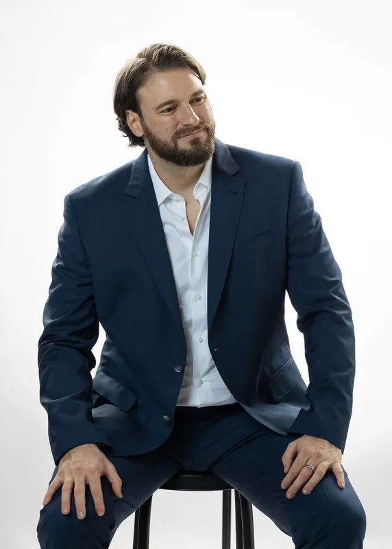 Seated on a stool at an angle. White background reference photo from an AI model training photoshoot at the MRPS studio in Dubai.