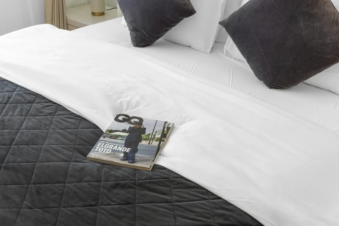 Bed detail with magazine and cushions in a Your Stay Apartments one-bedroom at Sky Gardens, DIFC, Dubai.
