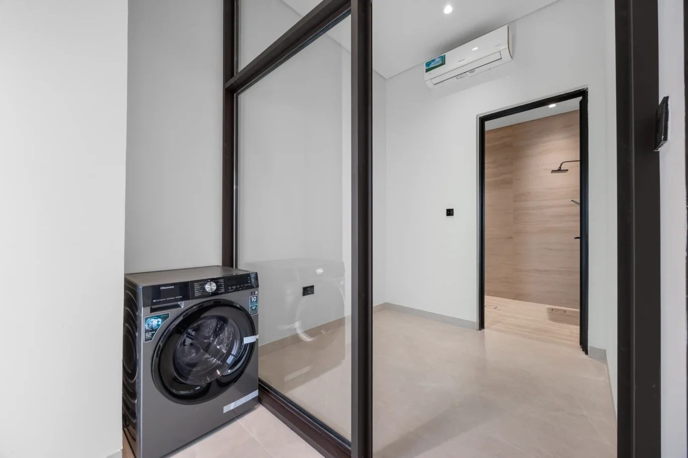Laundry room with a washing machine and glass partition, unfurnished five-bedroom villa in Al Furjan, Dubai.