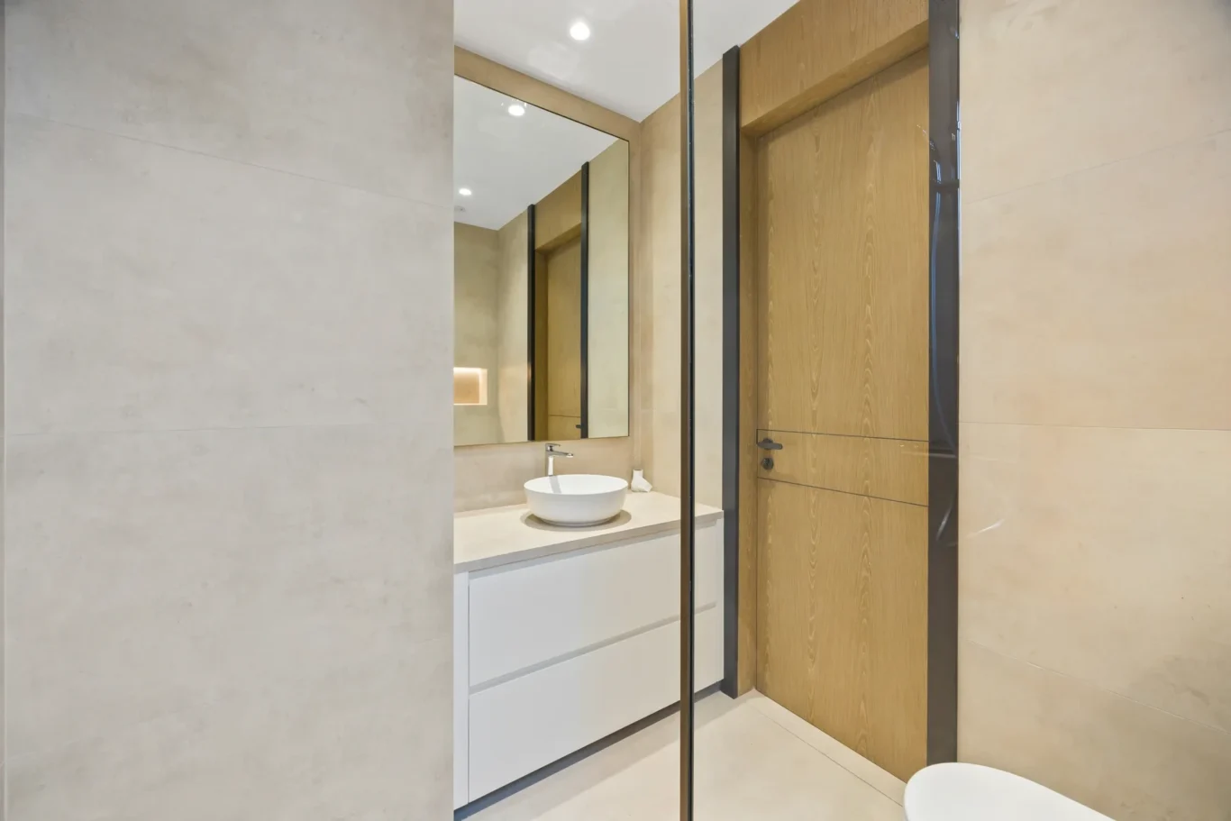 Bathroom with a vessel basin, mirror and wood door, luxury villa in Jumeirah Islands, Dubai.
