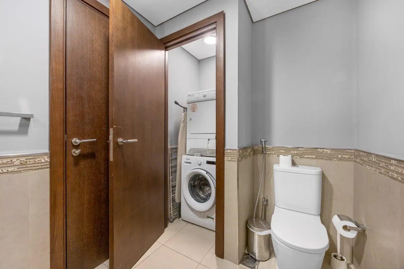 Washing machine and toilet in the guest washroom in a Your Stay Apartments one-bedroom at Burj Daman, DIFC, Dubai.