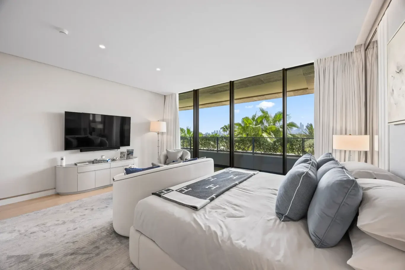 Master bed facing the TV and windows in a furnished three-bedroom residence at Atlantis The Royal, Palm Jumeirah, photographed for Apex Homes Real Estate.