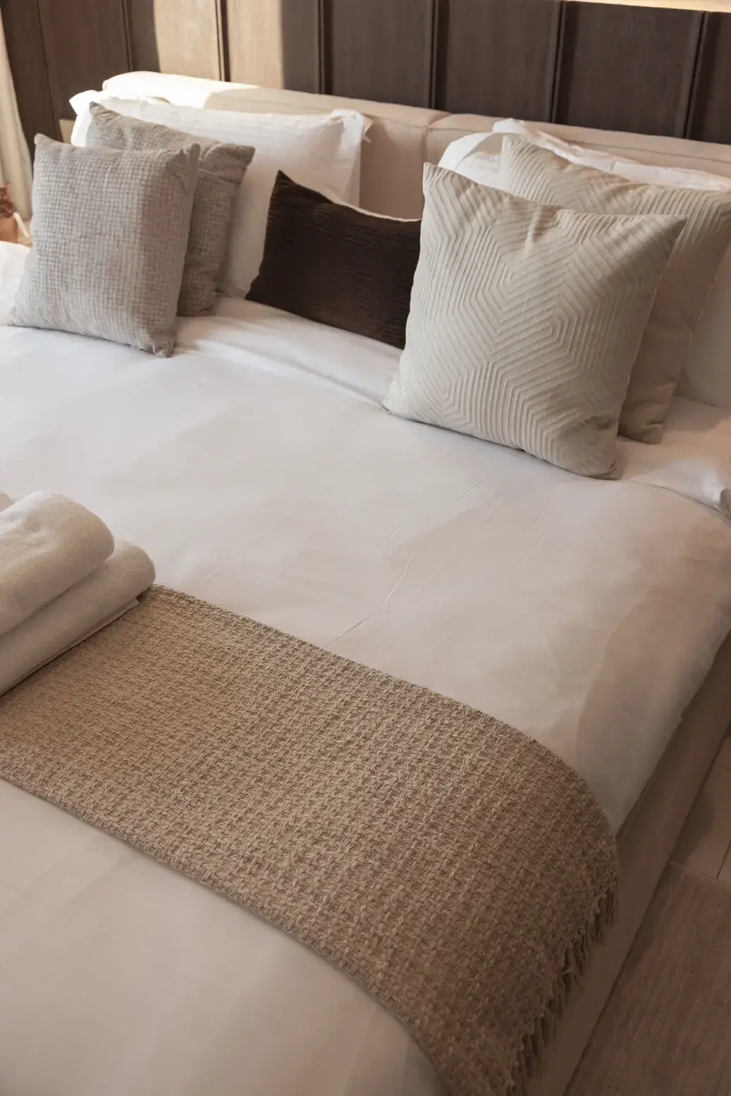 Master bed styled with cushions and a woven bed runner. Interior design photography for Aziza Home by MRPS in Dubai.