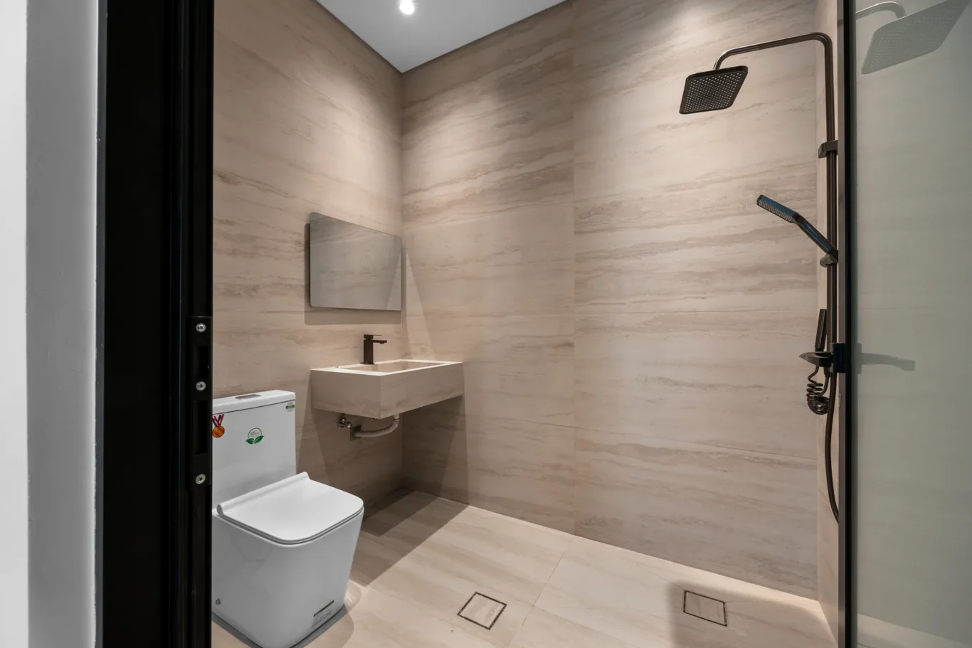 Staff bathroom with a shower and wood-effect tiles, unfurnished five-bedroom villa in Al Furjan, Dubai.