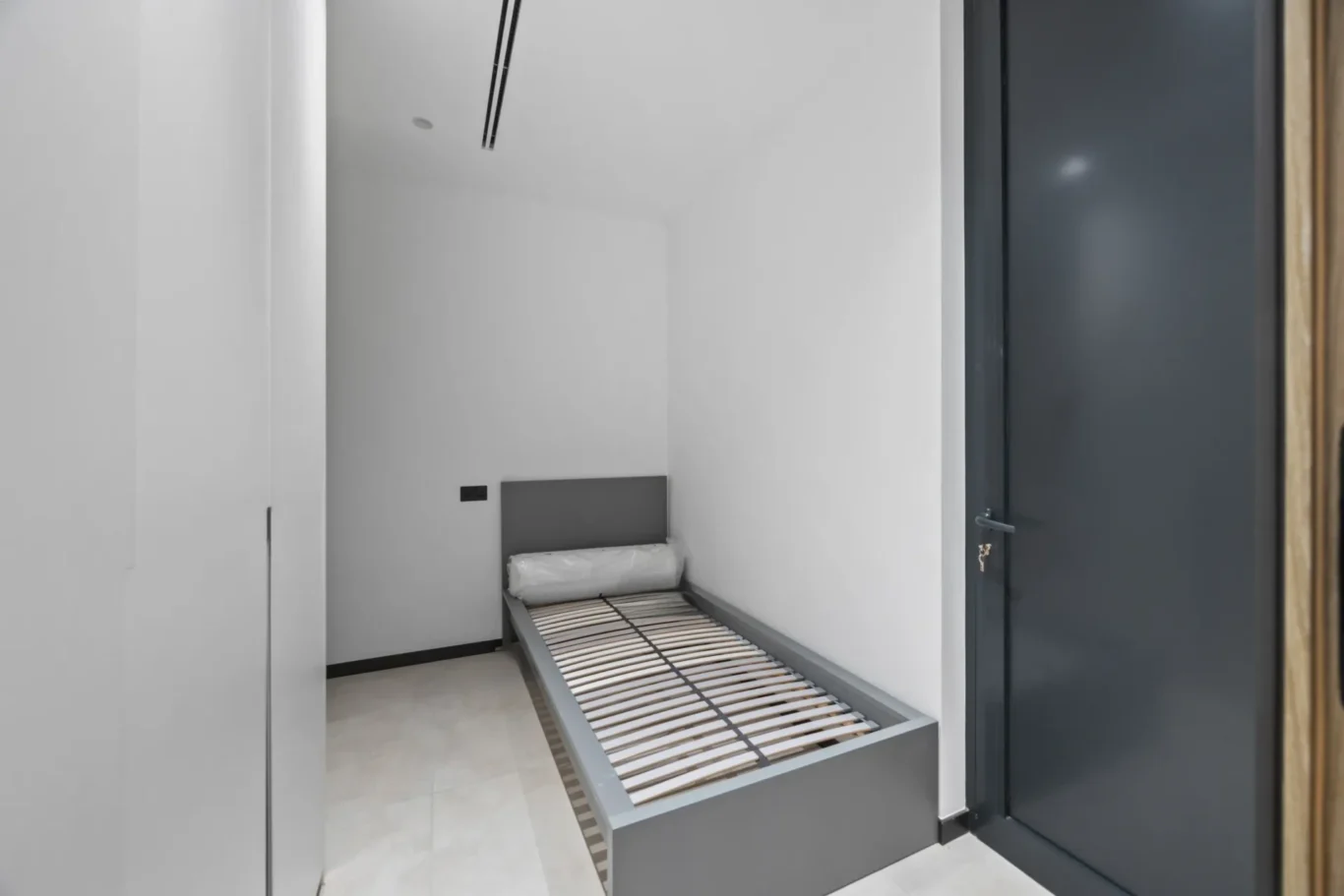 Staff room with a single bed and grey wardrobe door, luxury villa in Jumeirah Islands, Dubai.