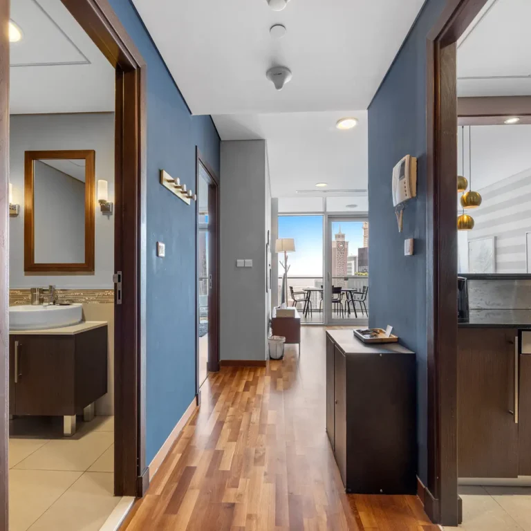 Entrance hall with wood floor and view to the living room in a Your Stay Apartments one-bedroom at Burj Daman, DIFC, Dubai.