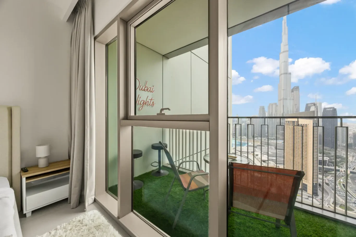 Master bedroom balcony with artificial grass, lounge chair and Burj Khalifa view. Day, twilight and night Airbnb photography by MRPS for Vista Haus Holiday Homes in Downtown Dubai.