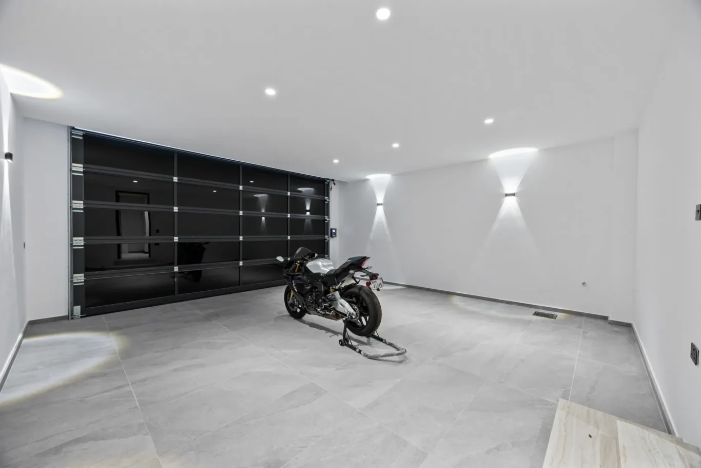 Garage with a glass sectional door, wall lights and a sports motorbike, luxury villa in Jumeirah Islands, Dubai.