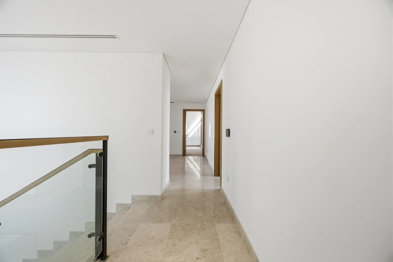 First floor landing with glass balustrade staircase. Villa photography by MRPS in Dubai for ELITE Property Brokerage.