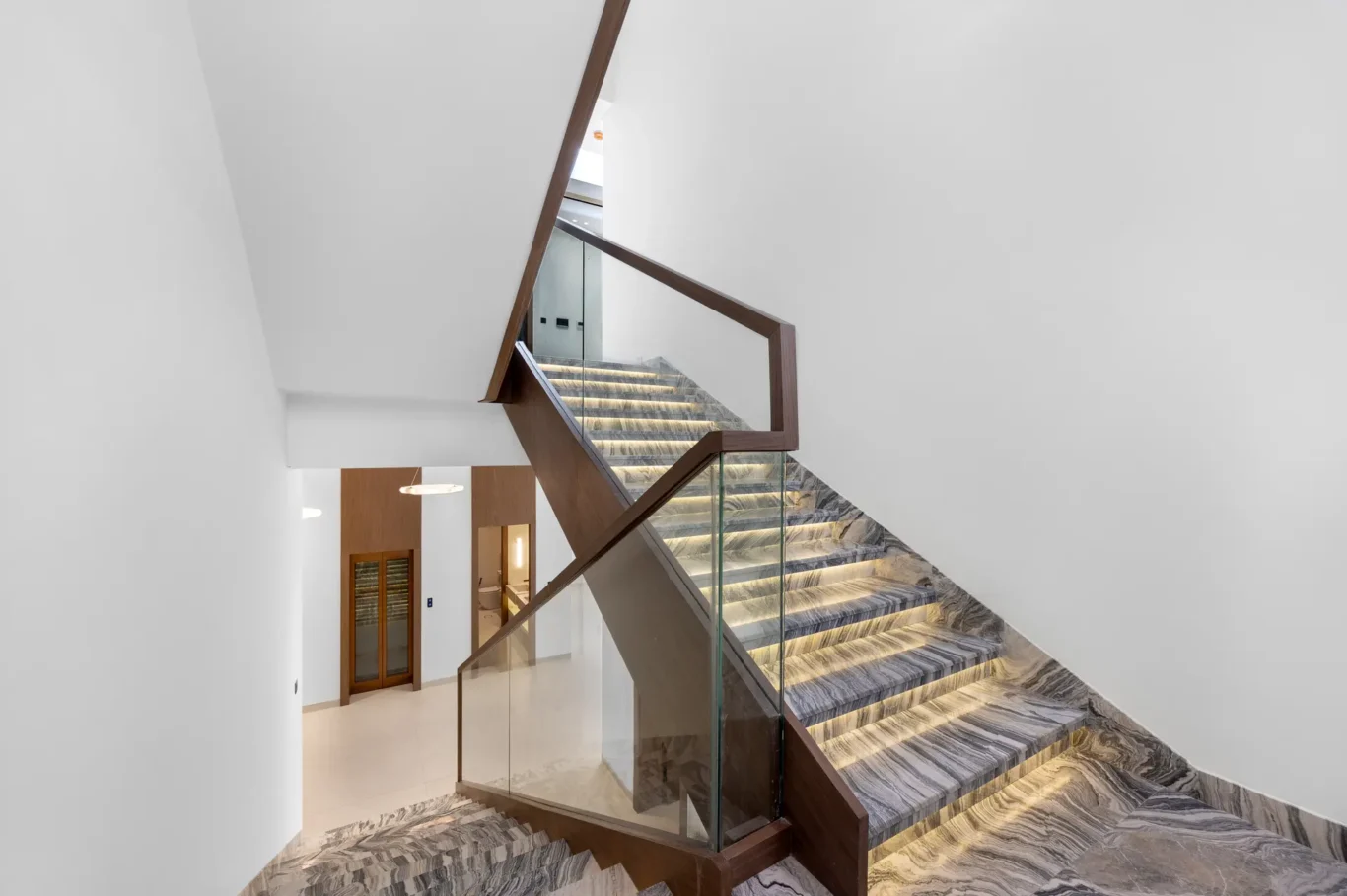 Marble staircase and glass balustrade seen from above, unfurnished five-bedroom villa in Al Furjan, Dubai.