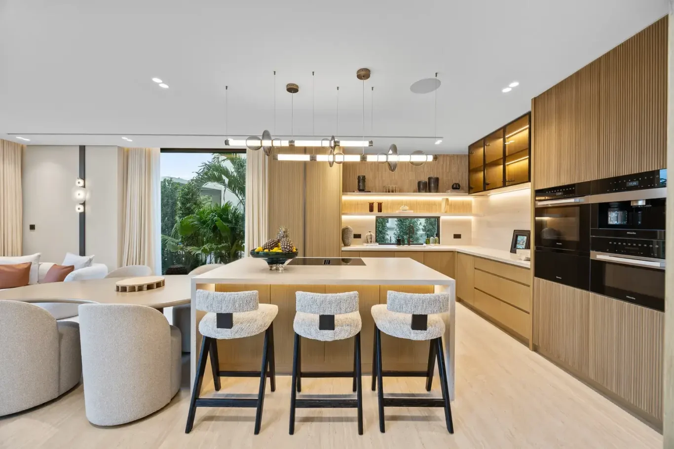 Open kitchen with an island, bar stools and built-in ovens, luxury villa in Jumeirah Islands, Dubai.