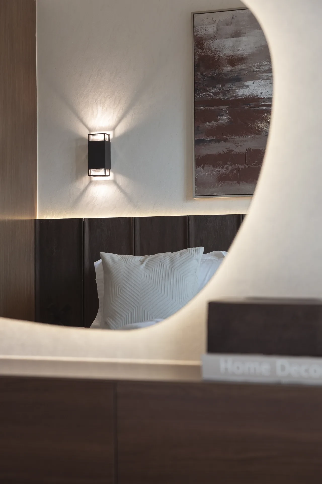 Backlit organic mirror reflecting the bedroom wall art. Interior design photography for Aziza Home by MRPS in Dubai.