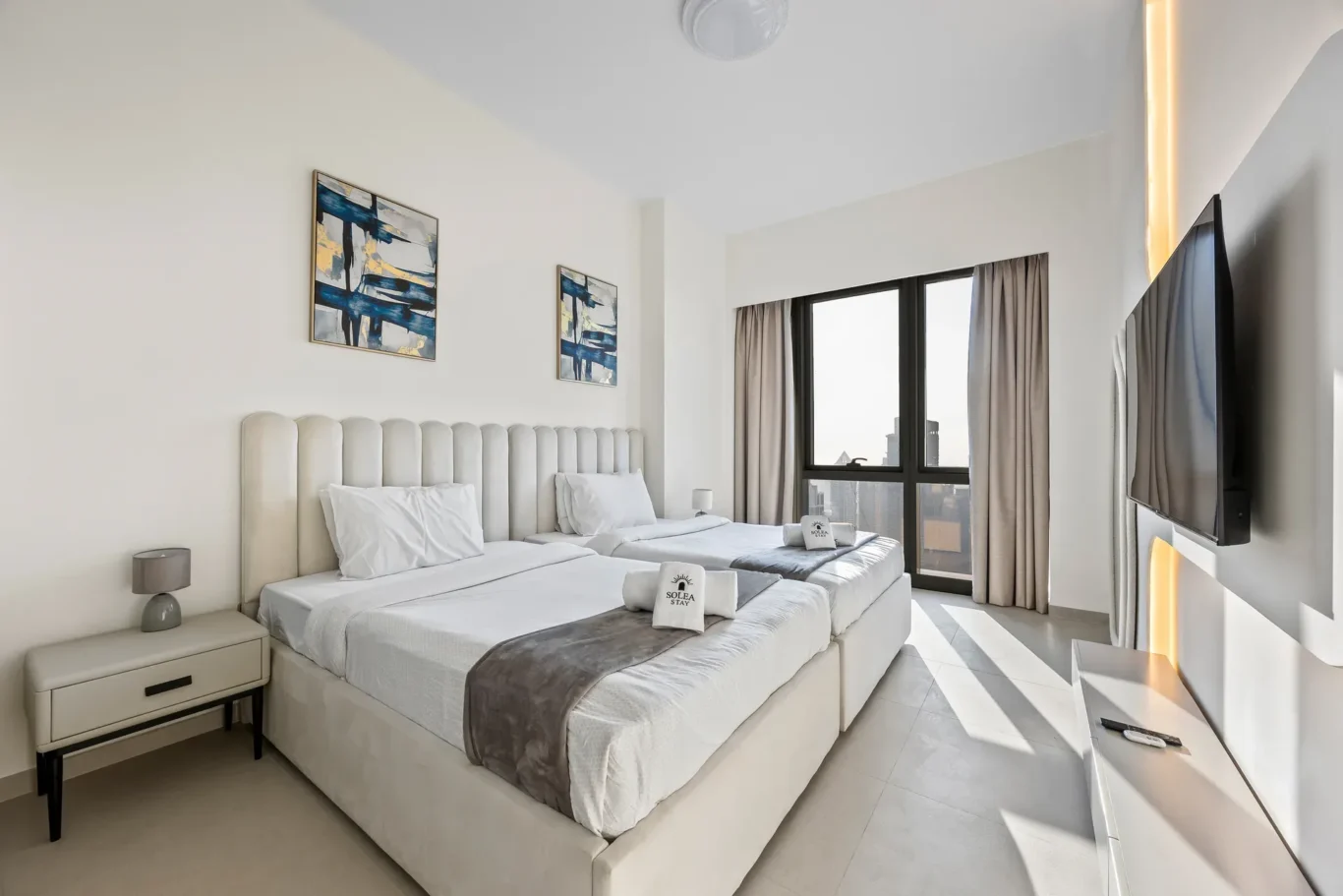 Second bedroom with upholstered headboard and blue abstract wall art. Airbnb photography by MRPS for Solea Stay in Dubai.