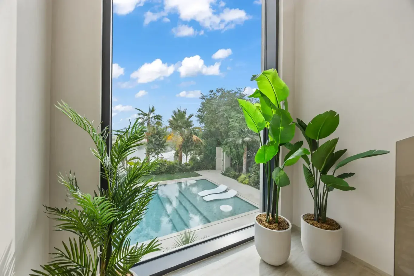 Tall window with plants overlooking the swimming pool, luxury villa in Jumeirah Islands, Dubai.