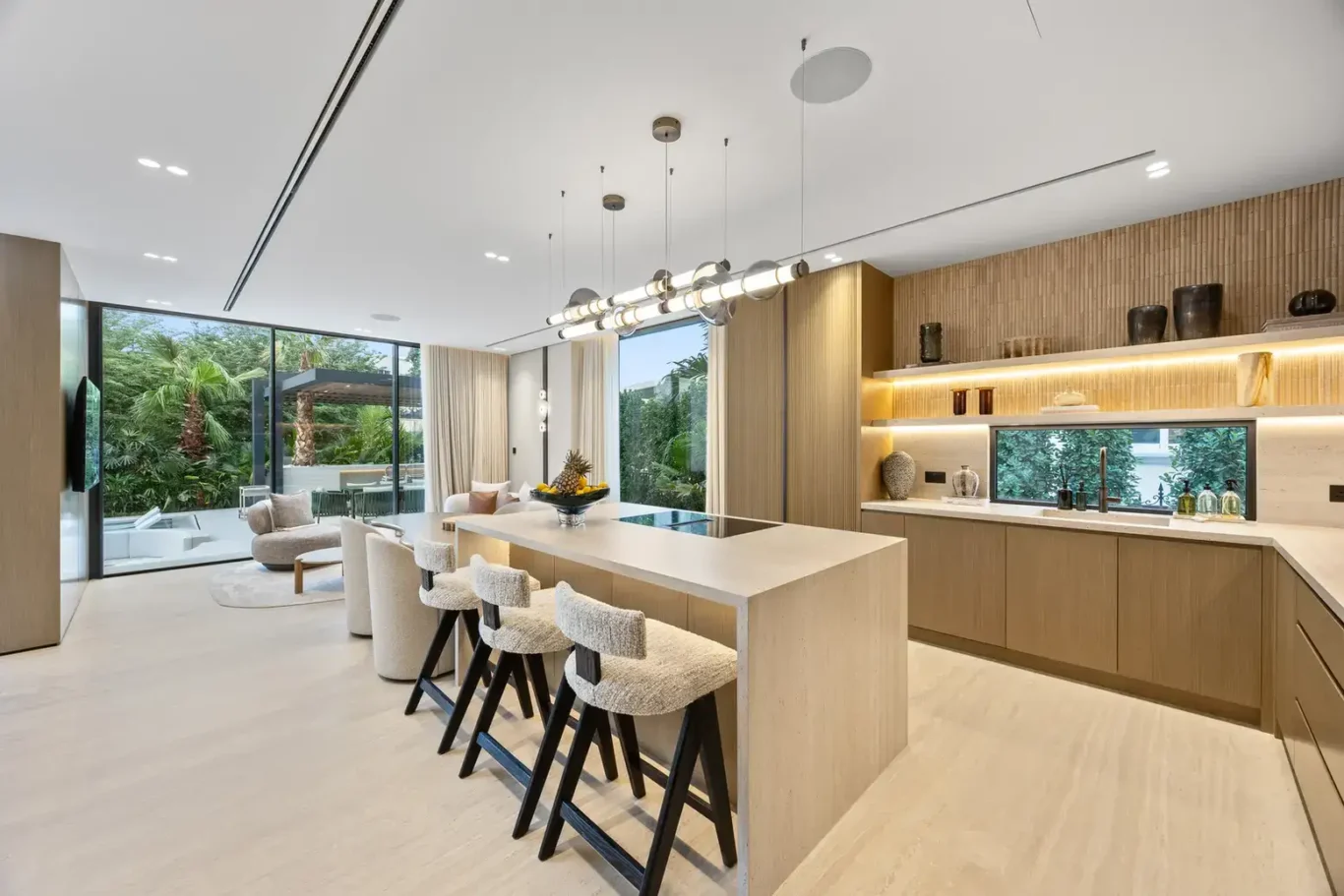 Kitchen island with bar stools under pendant lights, luxury villa in Jumeirah Islands, Dubai.