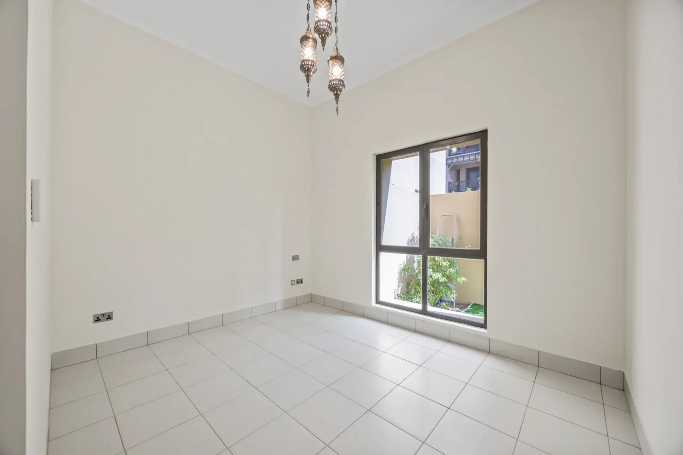 Second bedroom with garden-facing window in an unfurnished two-bedroom garden apartment in Old Town, Downtown Dubai, photographed for ELITE Property Brokerage.