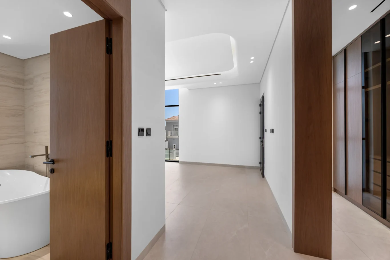 Master suite doorway with a glimpse of the freestanding bathtub, unfurnished five-bedroom villa in Al Furjan, Dubai.