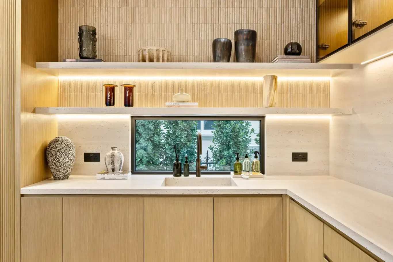 Kitchen counter with lit open shelves and a garden window, luxury villa in Jumeirah Islands, Dubai.
