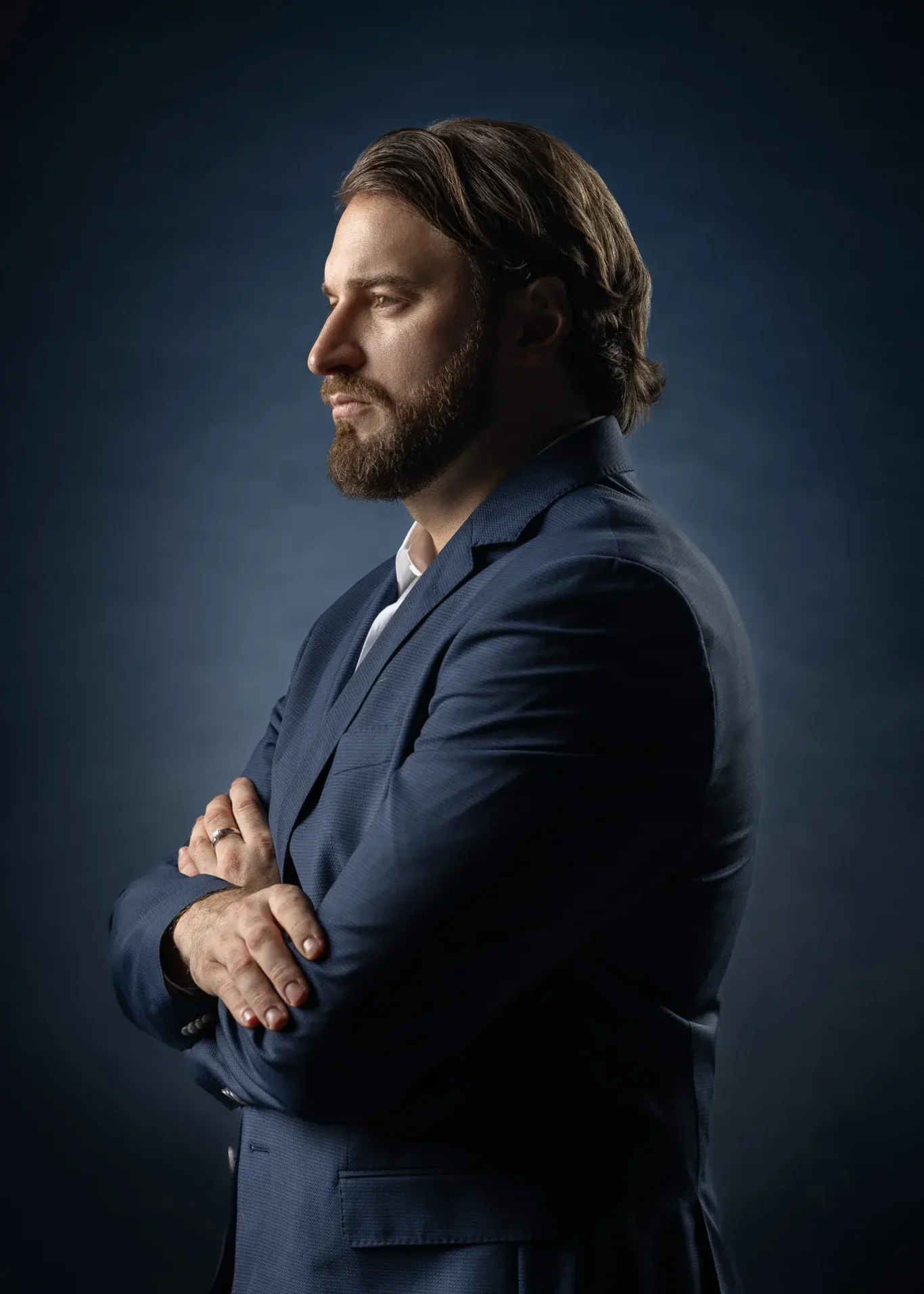 Profile portrait with arms crossed on a dark blue backdrop. Business portrait from an AI digital twin photoshoot at the MRPS studio in Dubai.