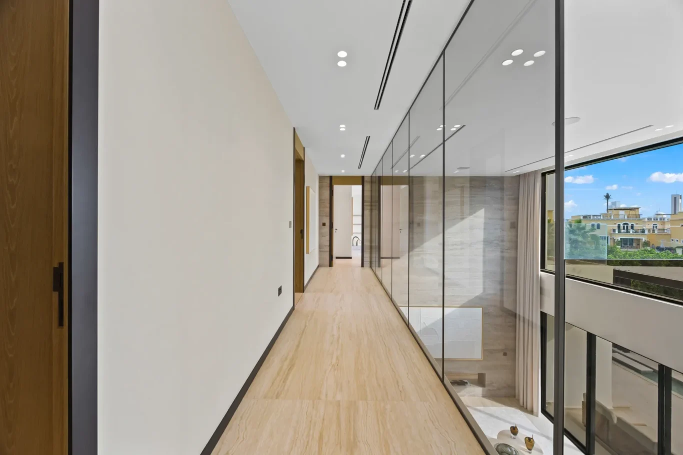 Upper floor corridor with glass walls and garden views, luxury villa in Jumeirah Islands, Dubai.