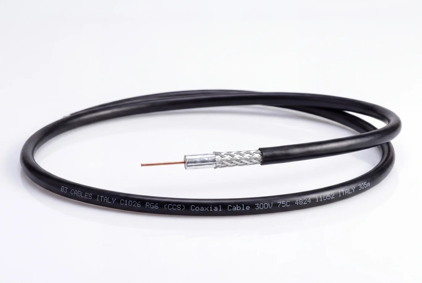Studio product photo of a coiled black RG6 coaxial cable with braid and centre conductor exposed.