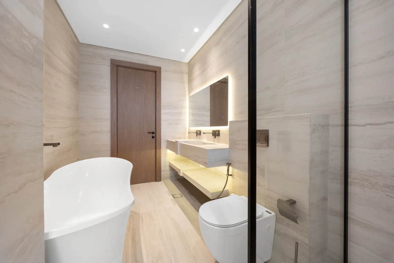 Master bathroom with a freestanding bathtub and backlit mirror, unfurnished five-bedroom villa in Al Furjan, Dubai.