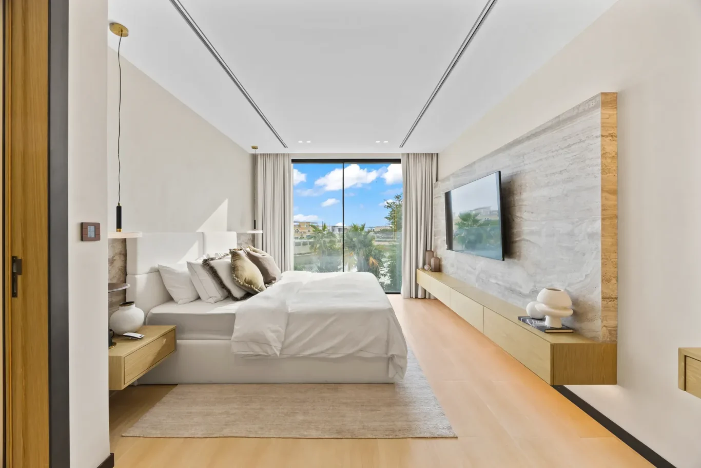 Upstairs bedroom with a stone TV wall and garden view, luxury villa in Jumeirah Islands, Dubai.