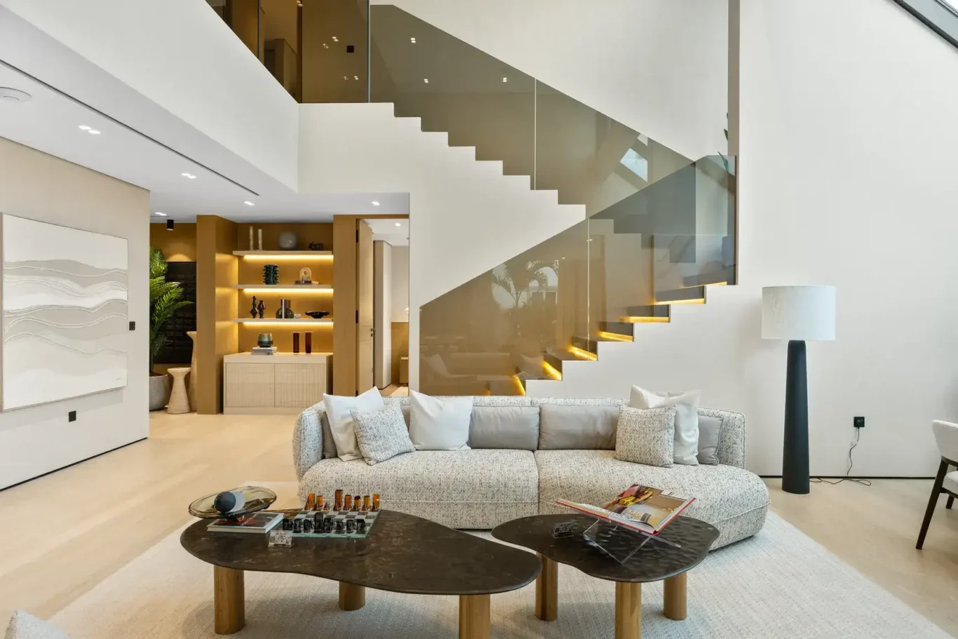 Living room with a curved sofa, stone coffee tables and floating stairs, luxury villa in Jumeirah Islands, Dubai.