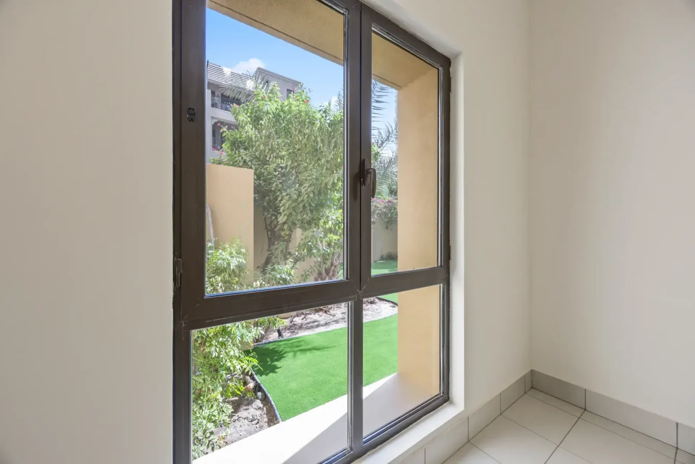Bedroom window opening onto the garden in an unfurnished two-bedroom garden apartment in Old Town, Downtown Dubai, photographed for ELITE Property Brokerage.