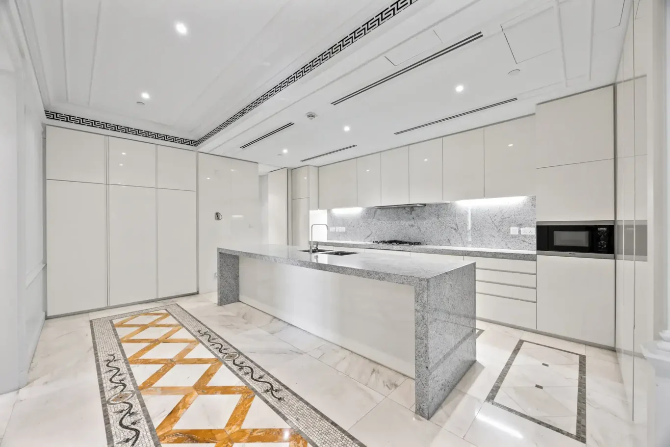 Show kitchen with a marble island and inlaid marble floor in a three-bedroom residence at Palazzo Versace Dubai, Jaddaf Waterfront, photographed for Concierge Auctions.
