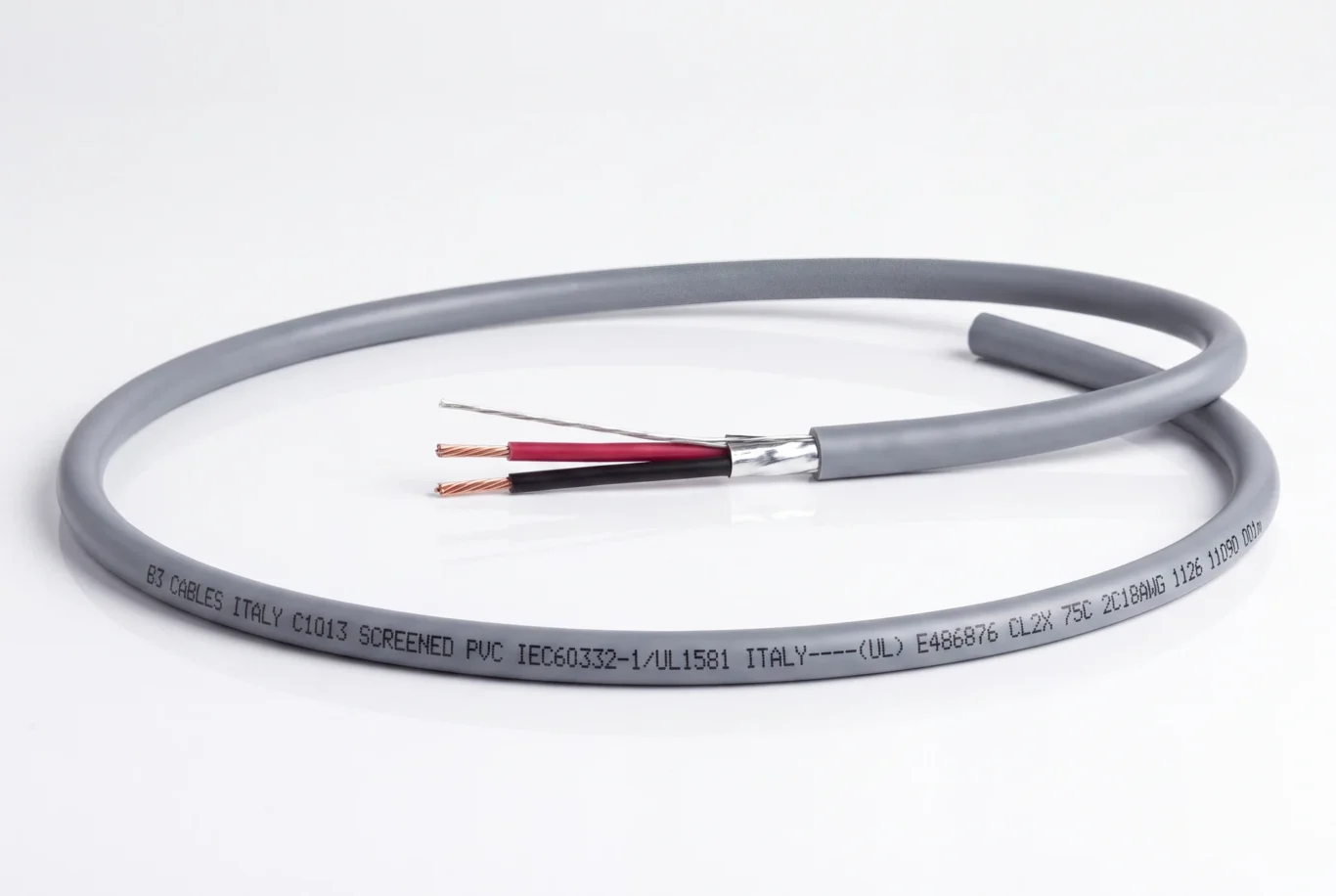 Studio product photo of a coiled grey screened two-core cable with red and black conductors.