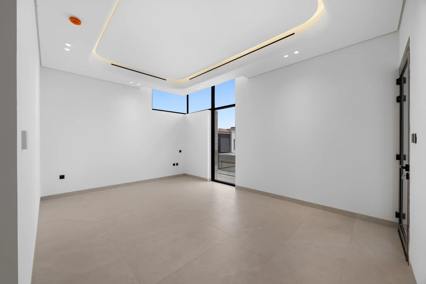 Empty bedroom with a corner window and cove lighting, unfurnished five-bedroom villa in Al Furjan, Dubai.
