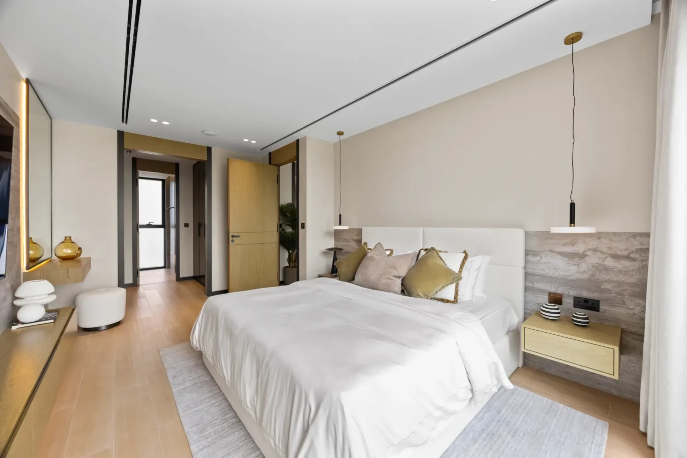 Upstairs bedroom with a white bed, pendant light and stone headboard wall, luxury villa in Jumeirah Islands, Dubai.