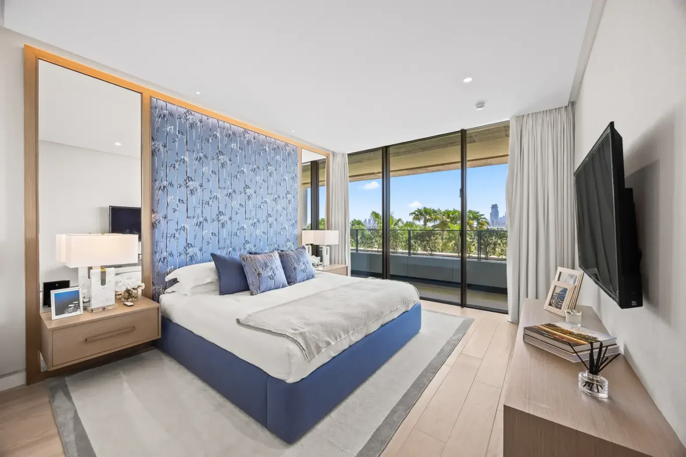 Bedroom with blue upholstered bed and wood panelled headboard wall in a furnished three-bedroom residence at Atlantis The Royal, Palm Jumeirah, photographed for Apex Homes Real Estate.