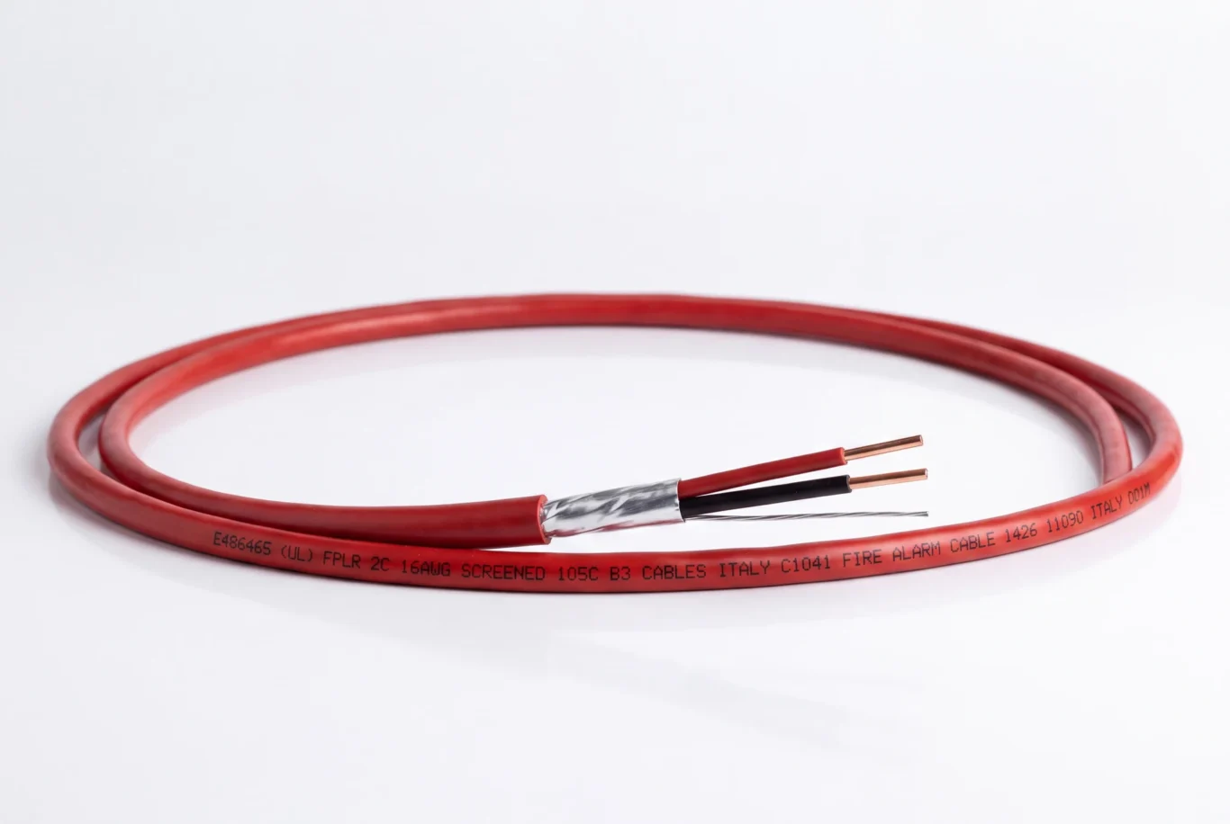 Studio product photo of a coiled red fire alarm cable with foil screen and copper conductors.