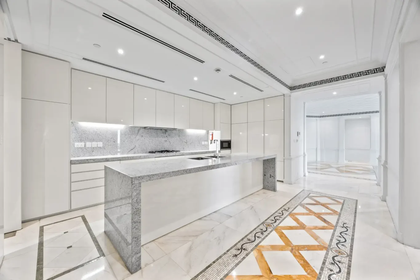 Kitchen island and full-height white cabinetry in a three-bedroom residence at Palazzo Versace Dubai, Jaddaf Waterfront, photographed for Concierge Auctions.