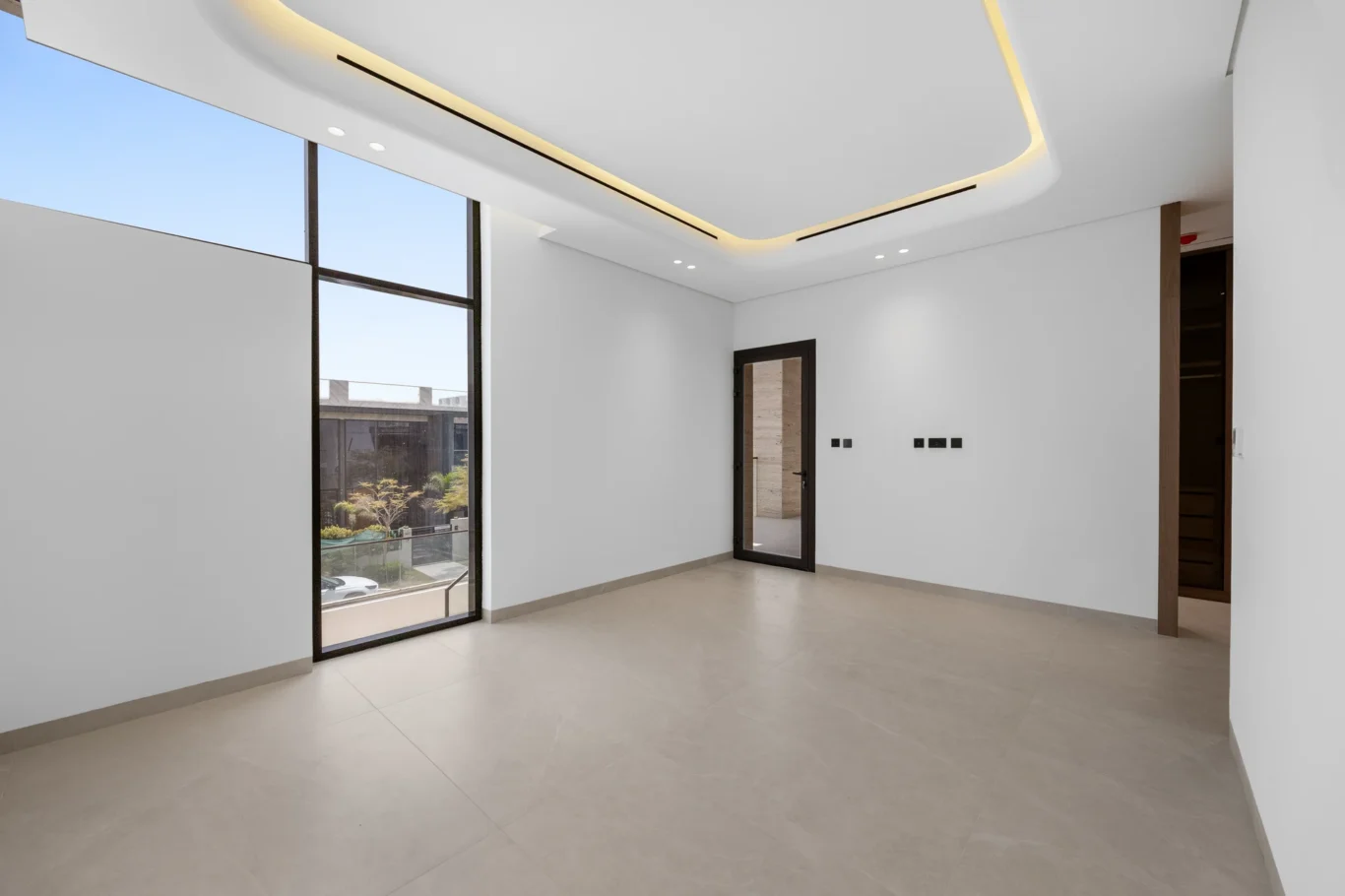 Bedroom with a tall window and balcony door, unfurnished five-bedroom villa in Al Furjan, Dubai.