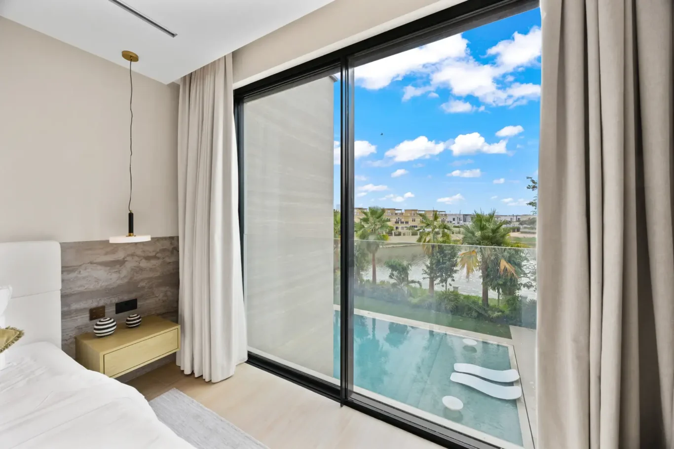 Bedroom window with a view over the pool and garden, luxury villa in Jumeirah Islands, Dubai.