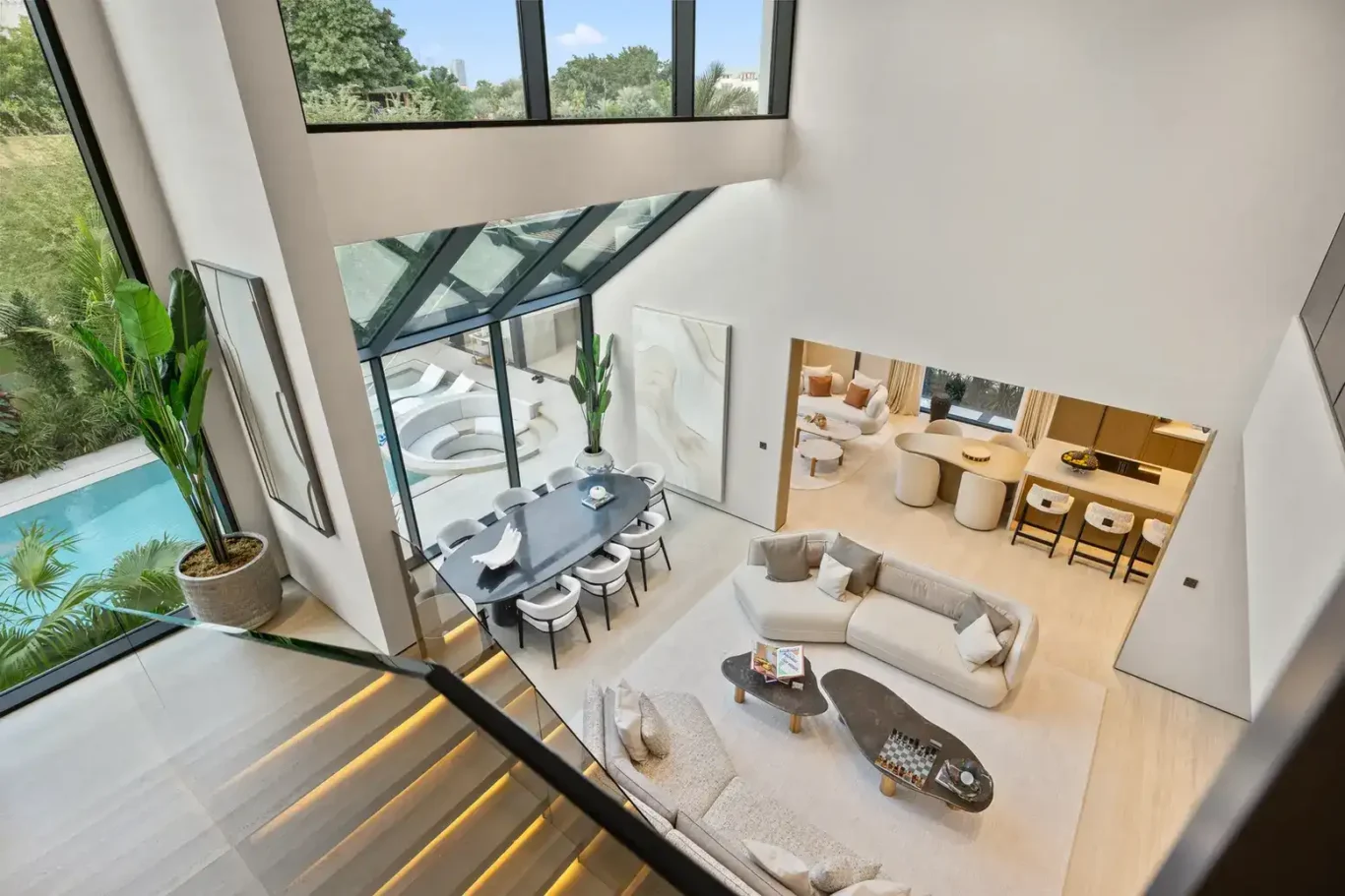 View from the mezzanine down to the living and dining areas through the slanted glass, luxury villa in Jumeirah Islands, Dubai.