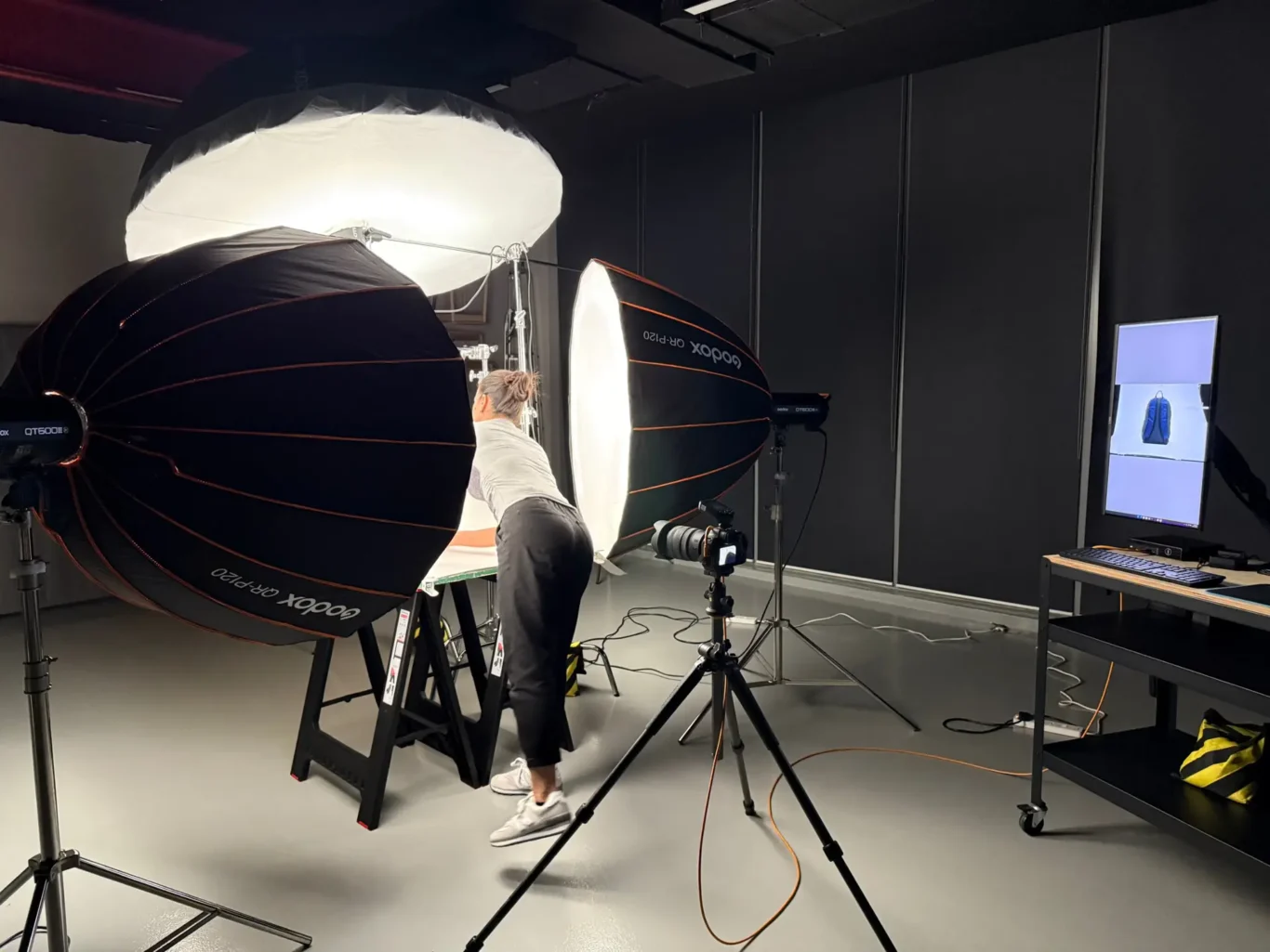 Photographer styling a navy New Balance backpack on a white sweep before the shot. Behind the scenes of the New Balance e-commerce product photography by MRPS in Dubai.