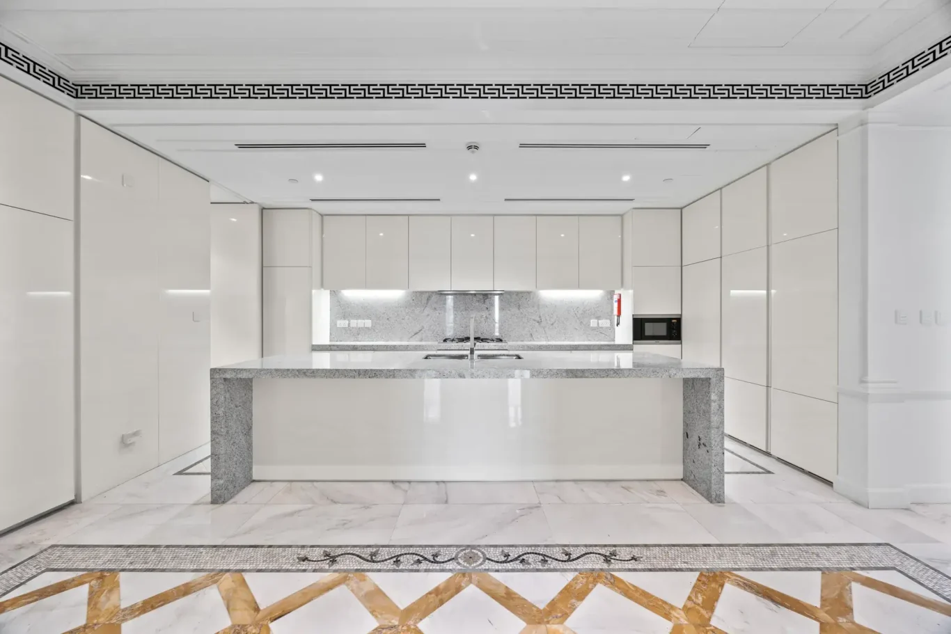 Kitchen with marble island and splashback in a three-bedroom residence at Palazzo Versace Dubai, Jaddaf Waterfront, photographed for Concierge Auctions.