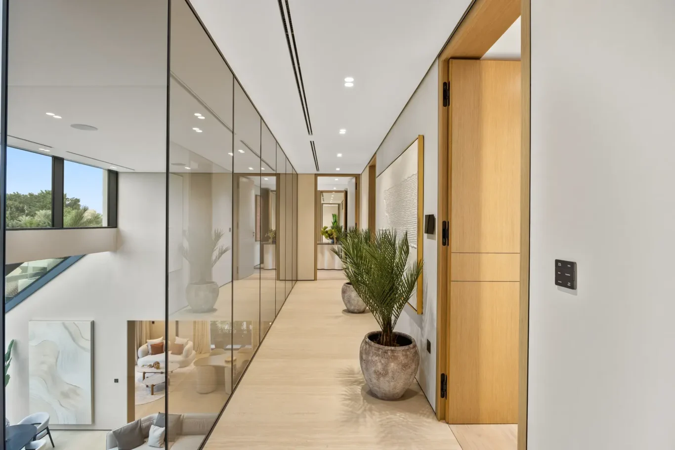 Upper floor corridor with a glass balustrade and a potted palm, luxury villa in Jumeirah Islands, Dubai.