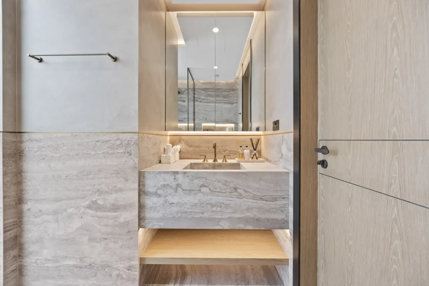 En-suite bathroom with a travertine vanity and lit mirror, luxury villa in Jumeirah Islands, Dubai.