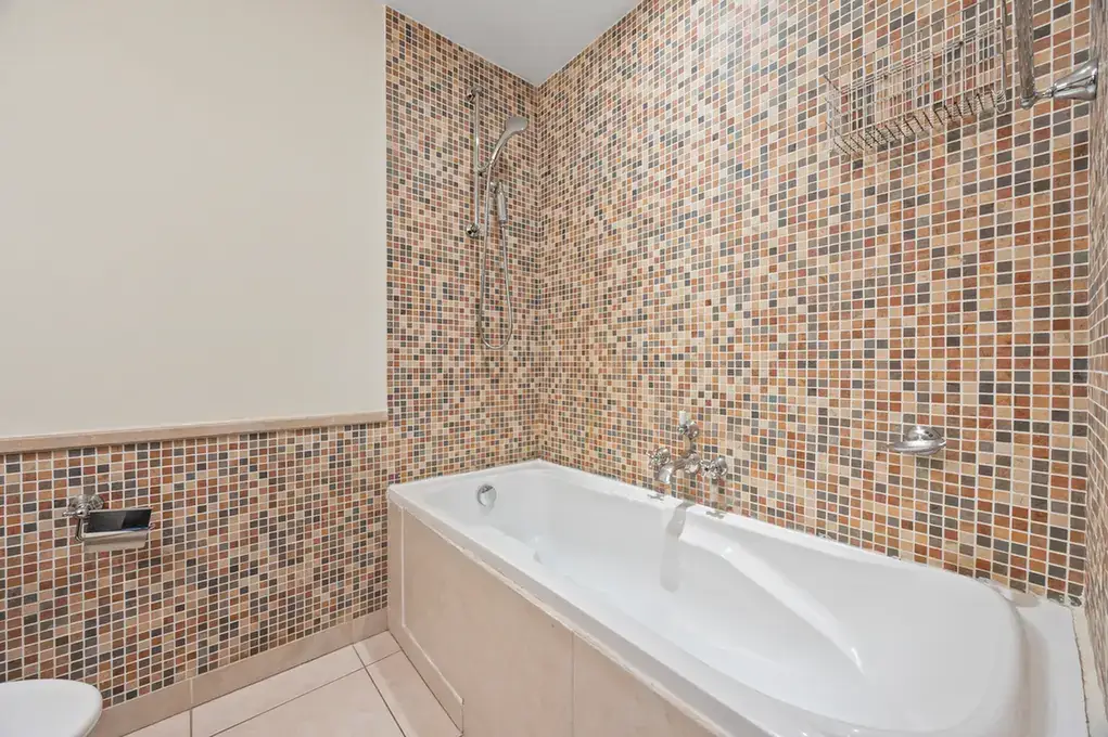 Bathtub with mosaic tile wall in an unfurnished two-bedroom garden apartment in Old Town, Downtown Dubai, photographed for ELITE Property Brokerage.