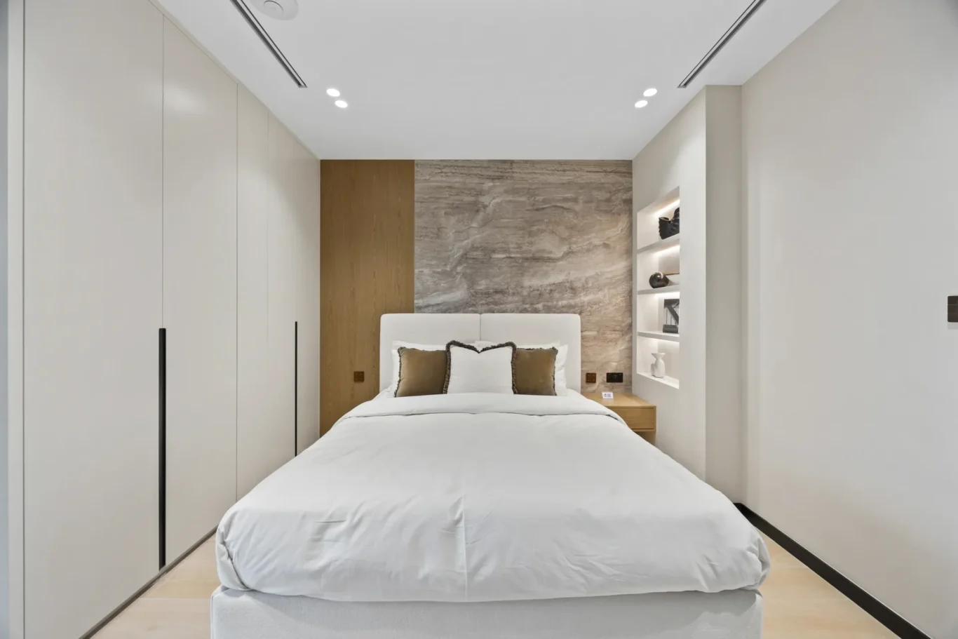 Bedroom with a stone headboard wall and built-in wardrobes, luxury villa in Jumeirah Islands, Dubai.