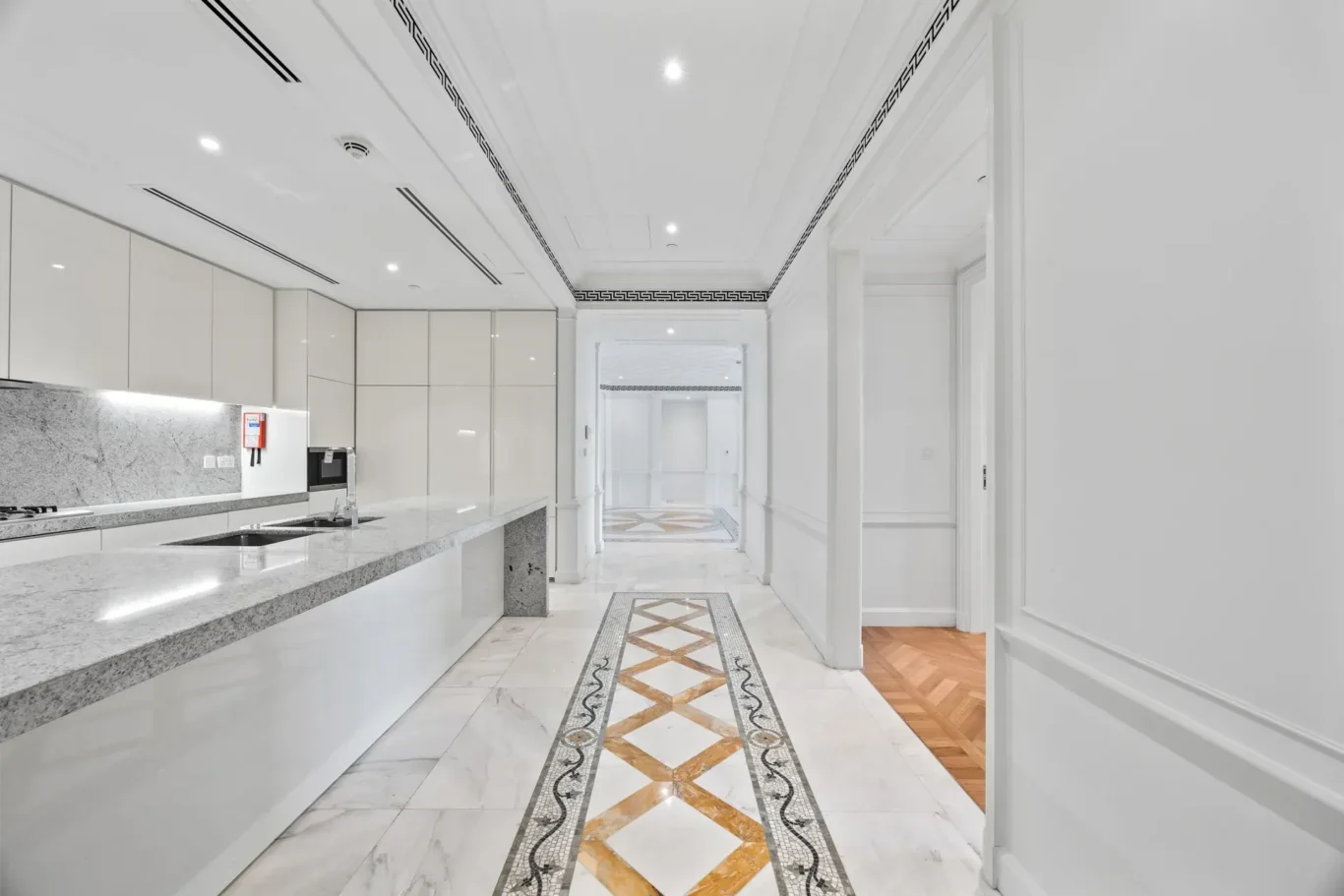 Kitchen galley leading to the service area in a three-bedroom residence at Palazzo Versace Dubai, Jaddaf Waterfront, photographed for Concierge Auctions.